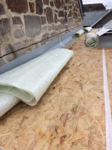 A sheet of fibreglass lies on a flat roof